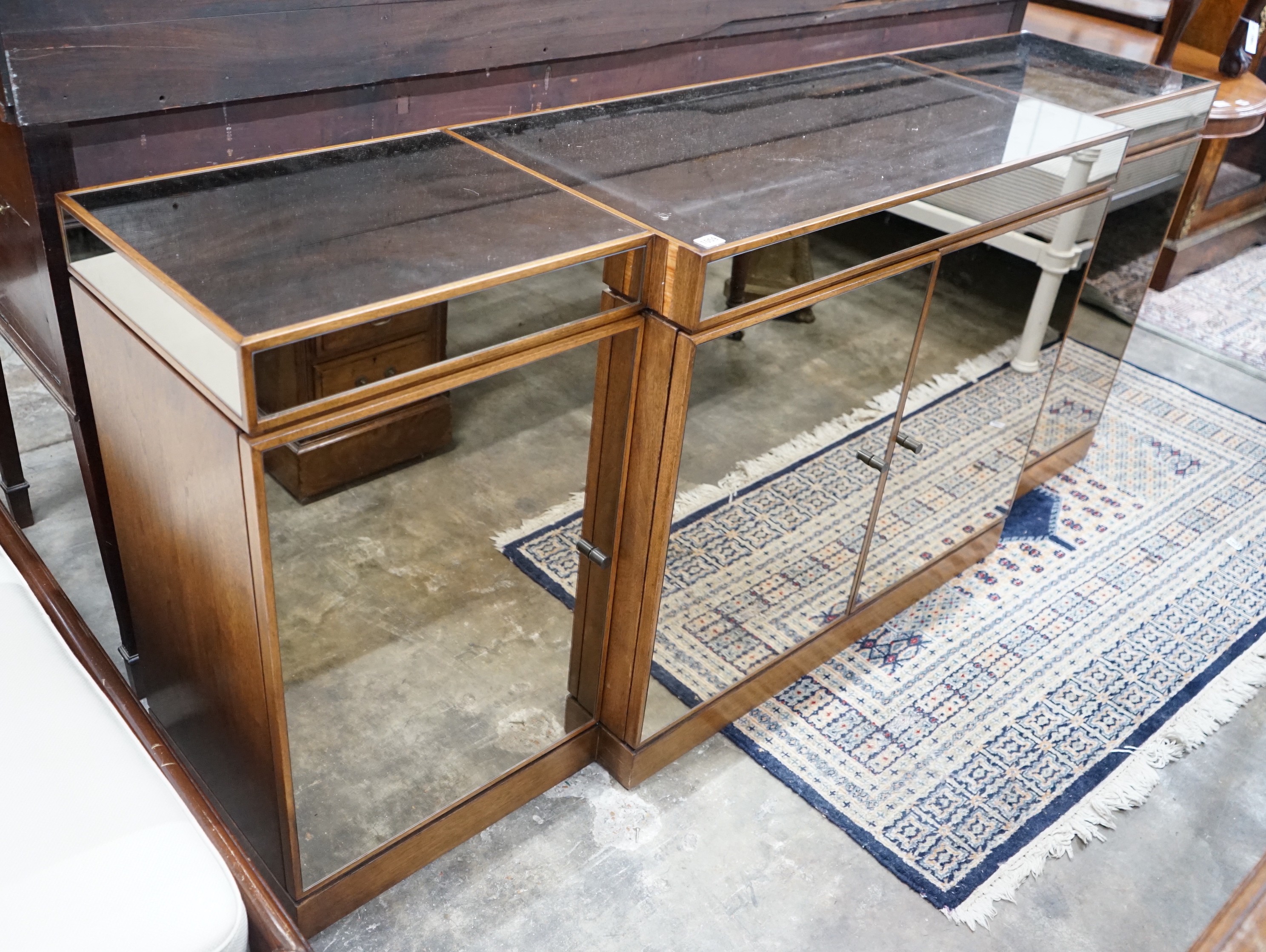 A contemporary mirrored walnut breakfront four door sideboard, width 200cms, depth 50cms, height 86cms.